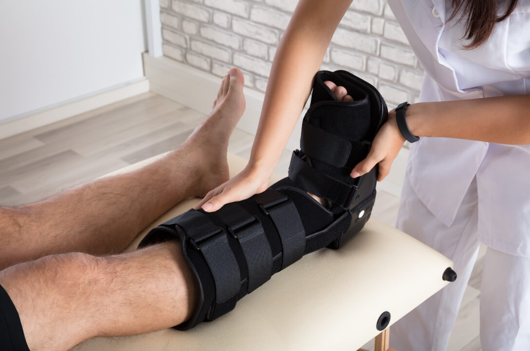 Orthopedic doctor examines patient's injured foot in a boot