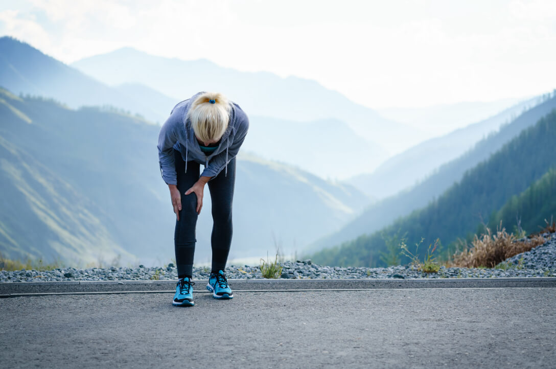 Orthopedic patient stops to hold injured knee while on a run in Alaska