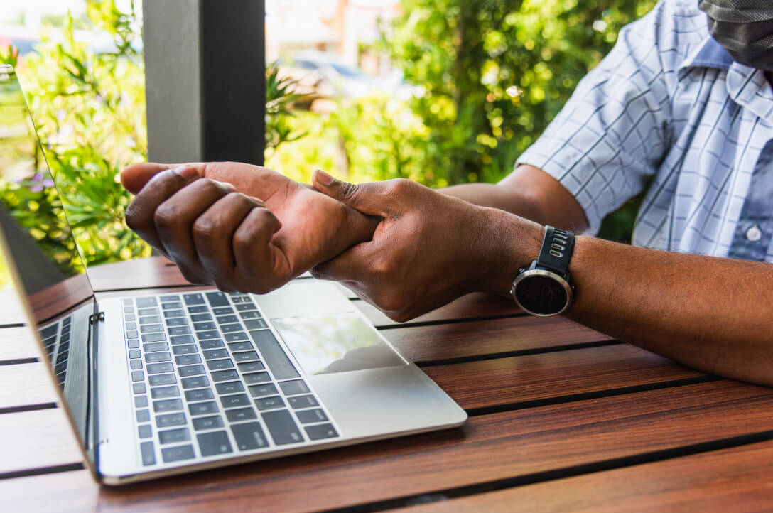 Orthopedic patient holds wrist while working on laptop